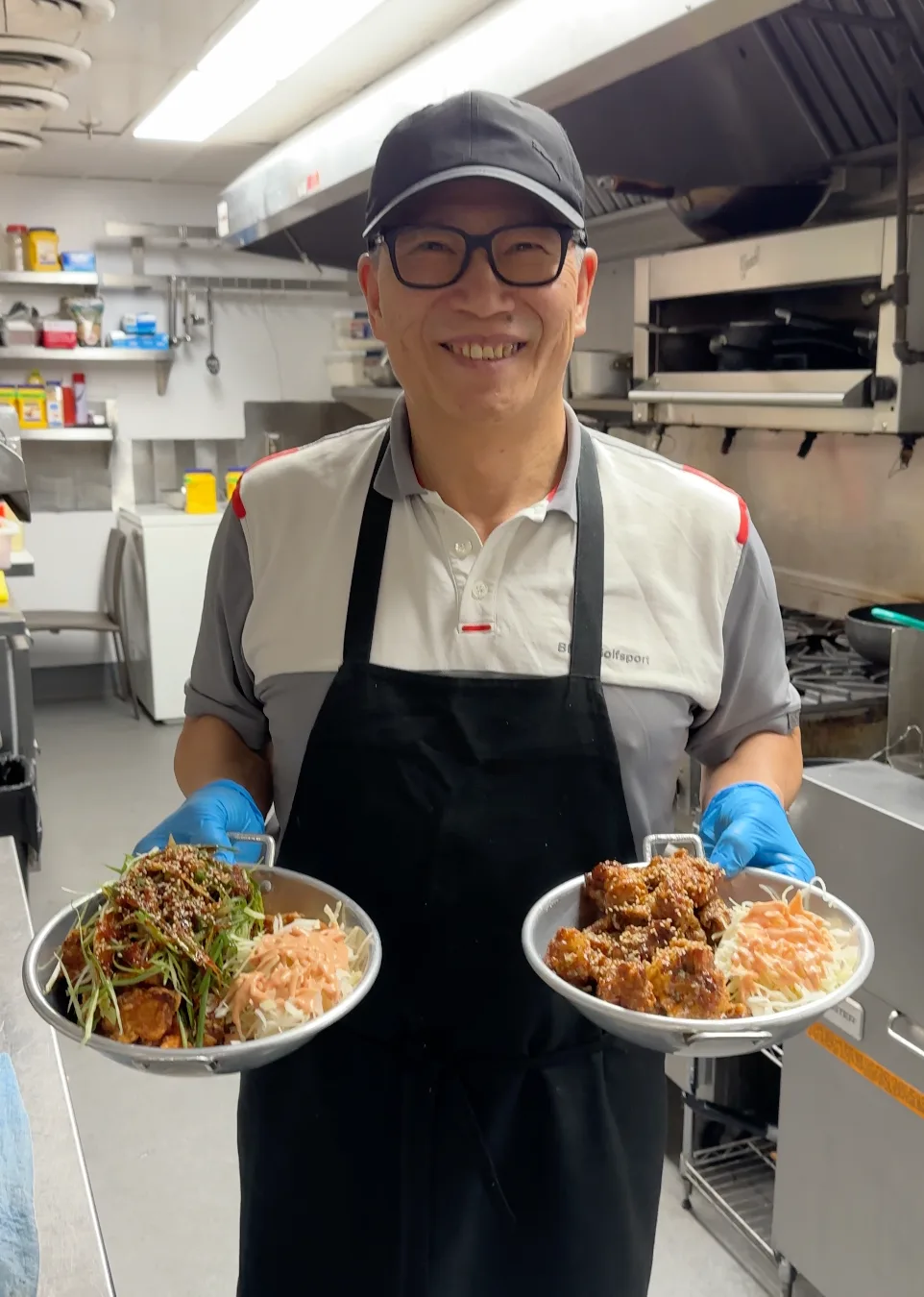 Mr. Kim in his kitchen holding two bowls of Korean fried chicken